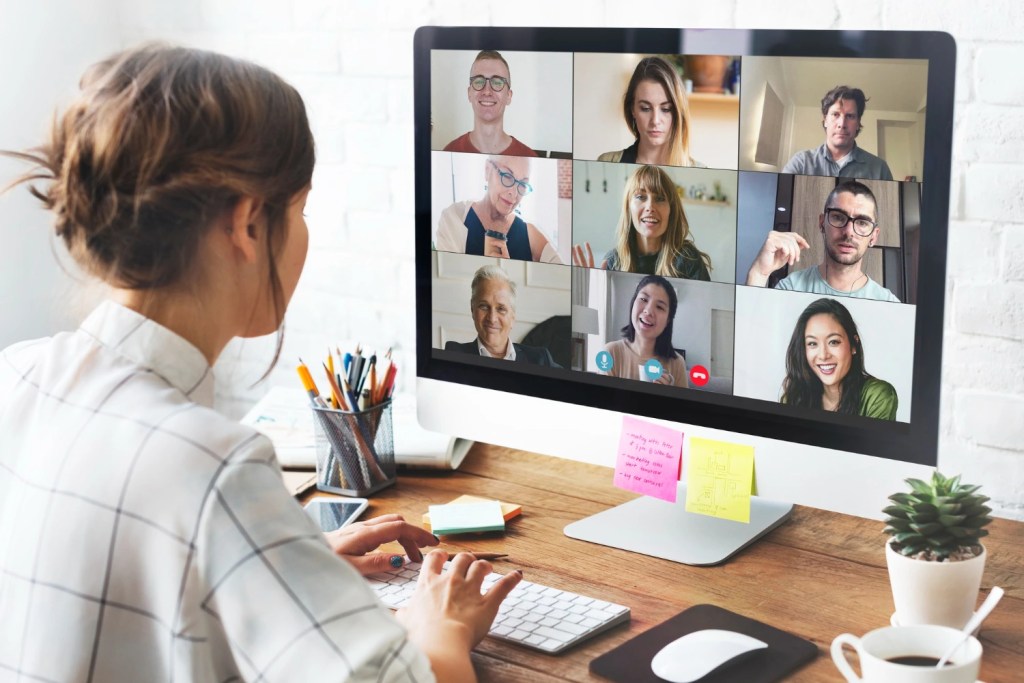 A woman sharing a screen and video on an online conferencing platform during a corporate meeting